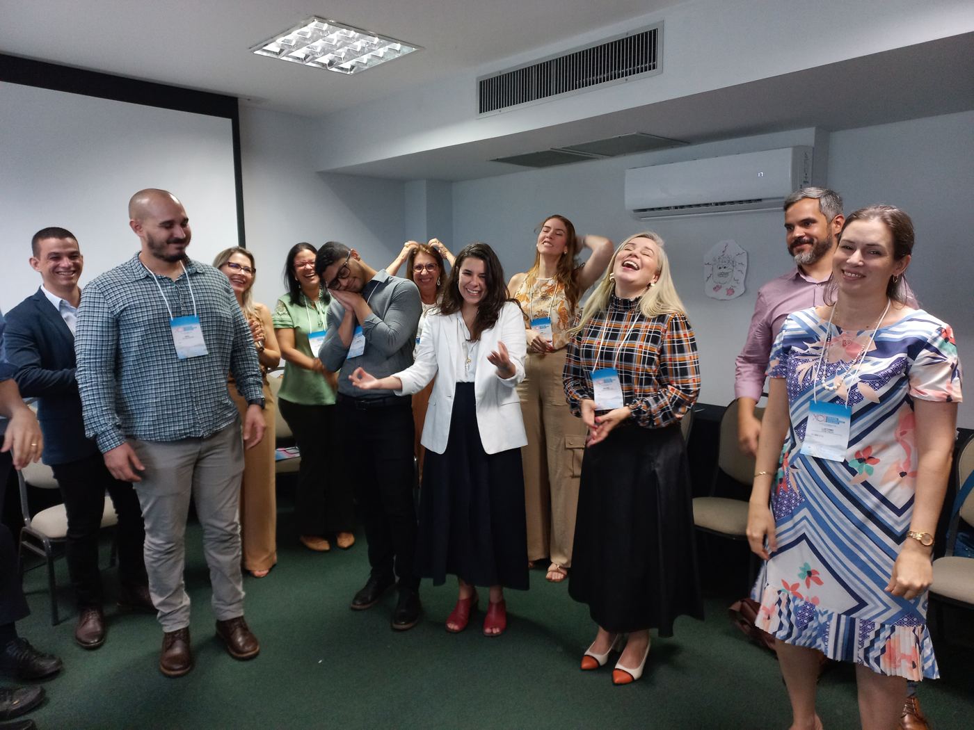Participantes em pé, rindo durante uma dinâmica de movimento